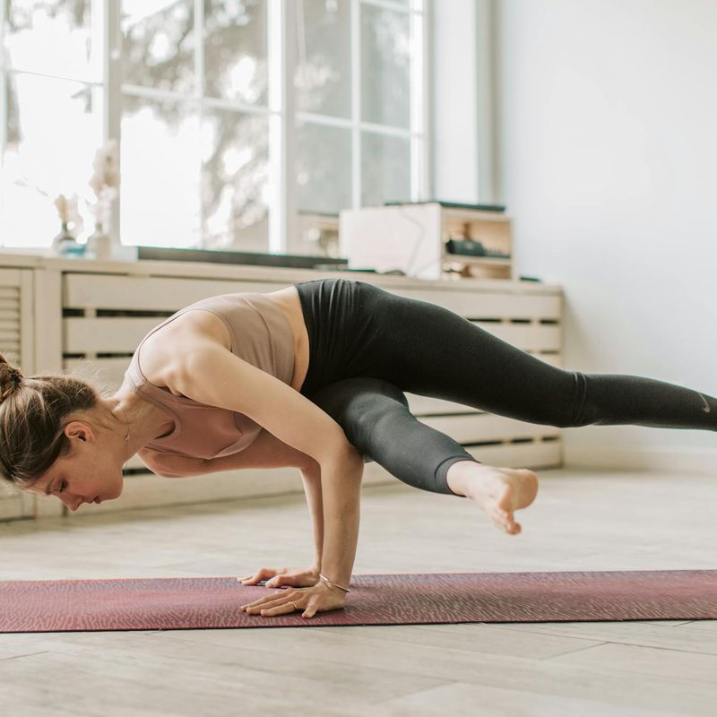 Woman maintaining a challenging balance yoga pose.
